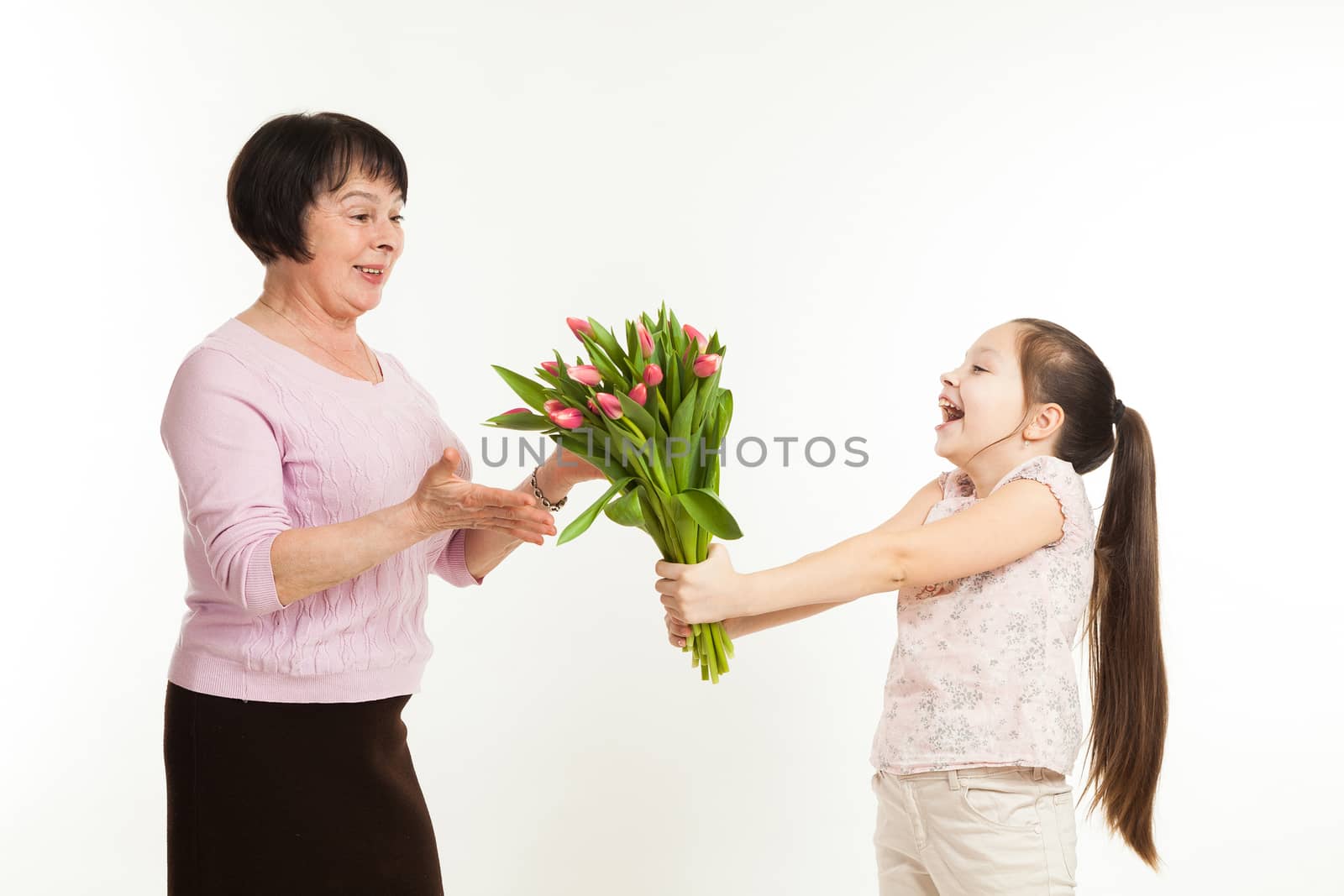 the granddaughter congratulates the grandmother and gives it flowers