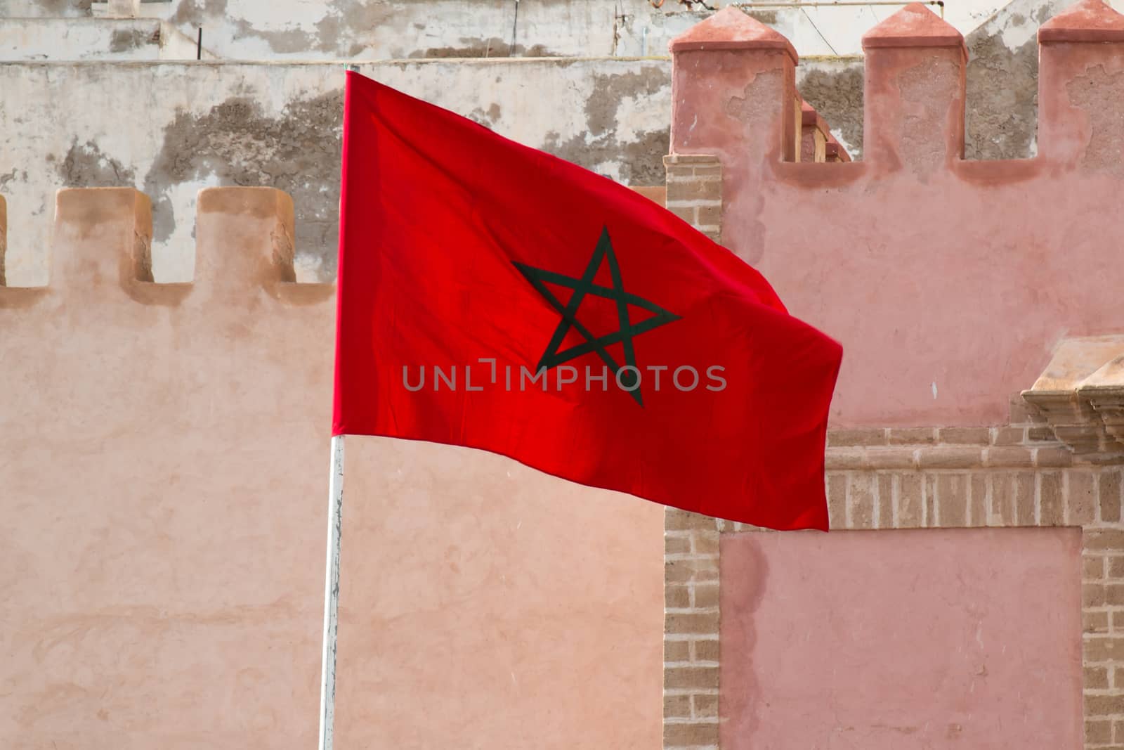 Wind waving the moroccan flag. Traditional architecture in the background.