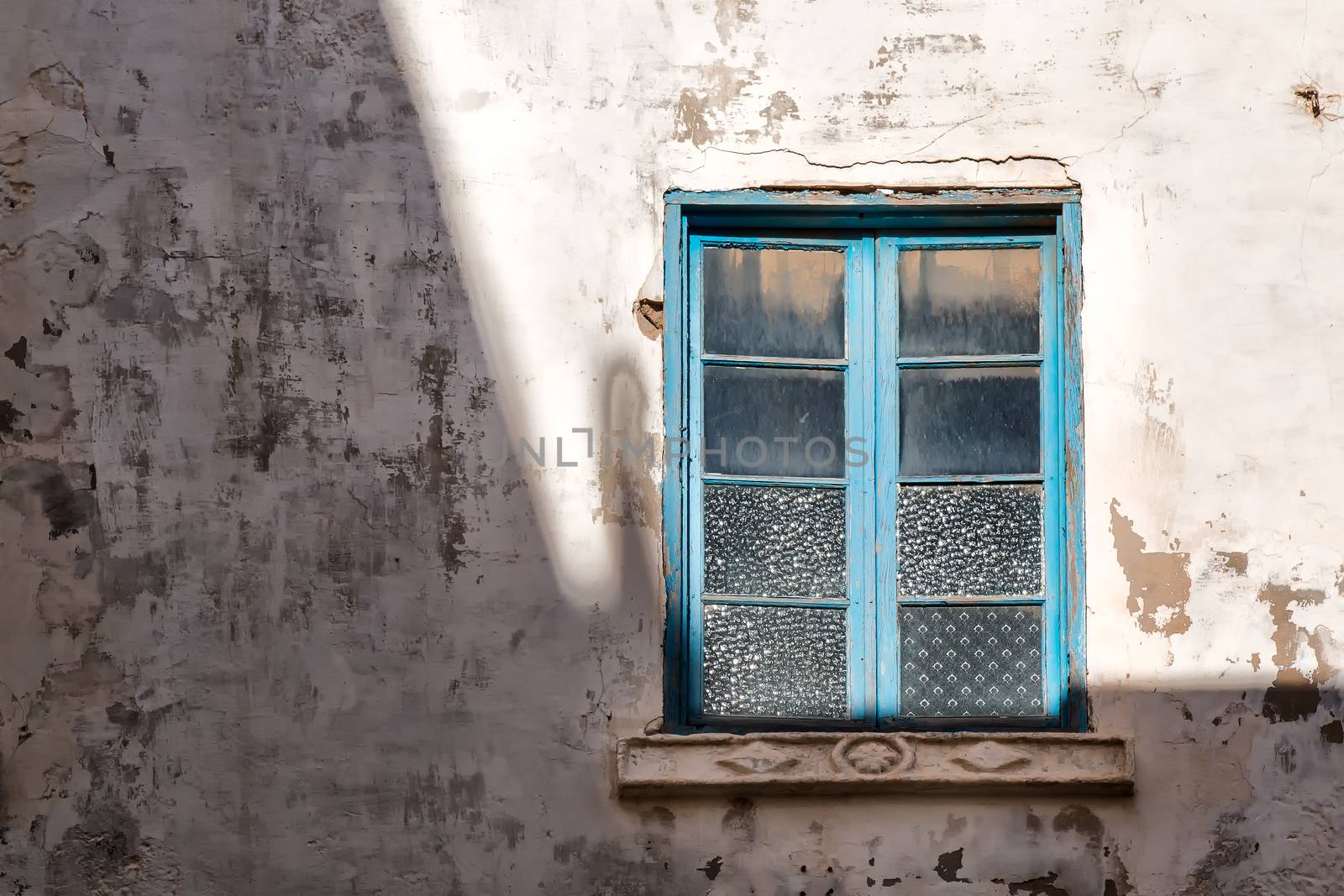 On the border of  light and shadow, blue framed window, reflecting the sunlight.