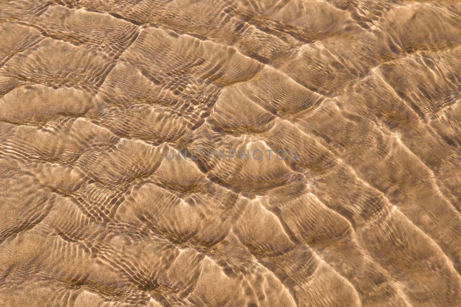 Golden fine sand on the shoreline, creating abstract pattern during the tide.