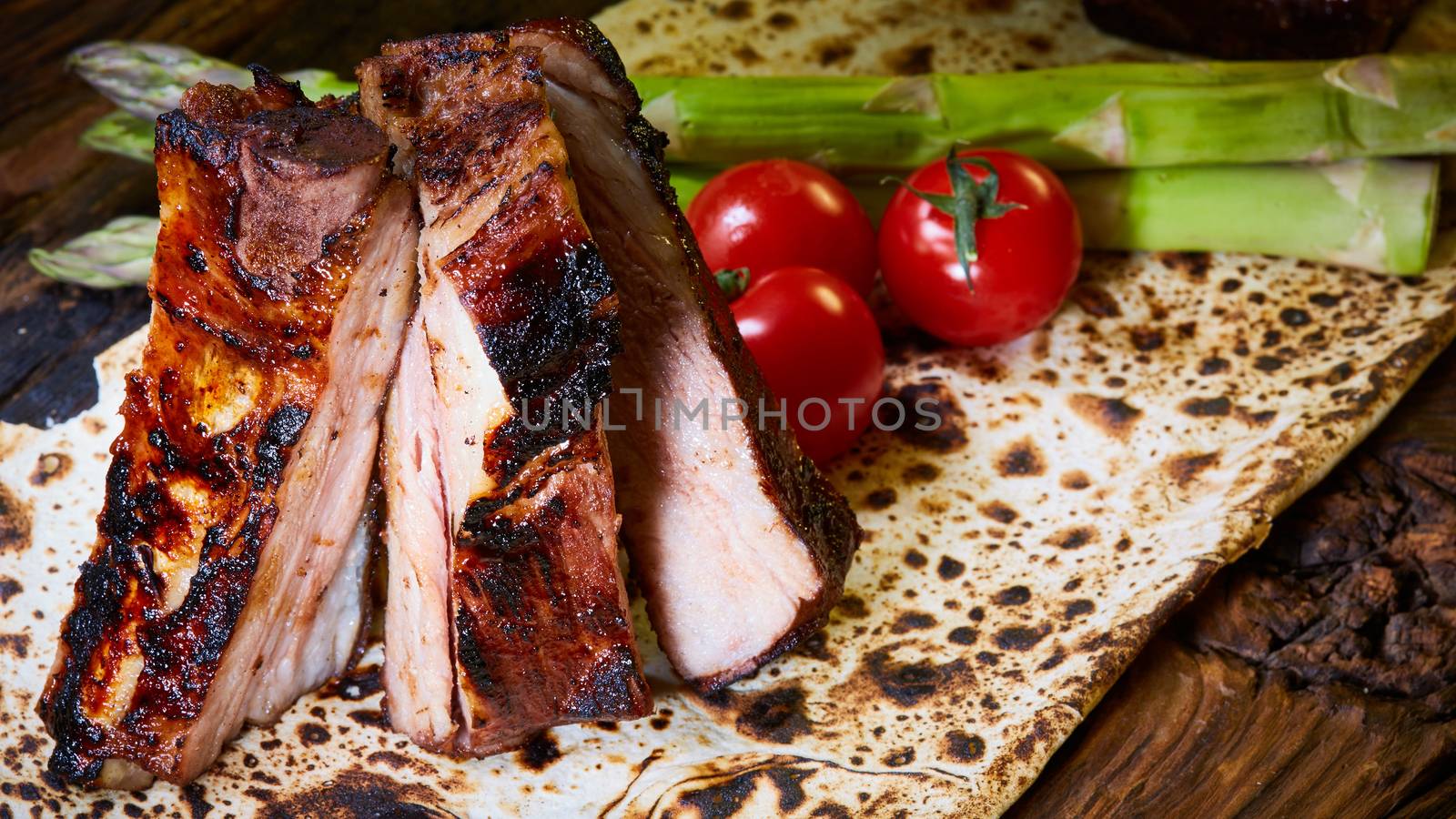 Grilled pork ribs on black cutting board.