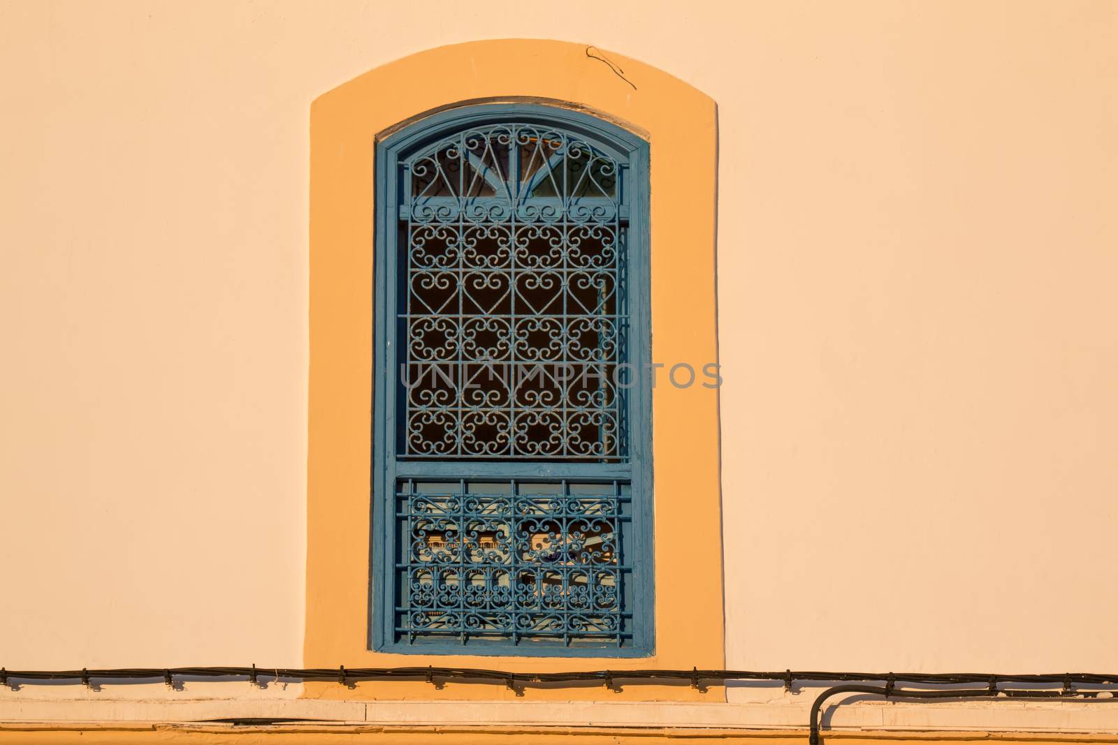 Contrast of the yellow facade with the traditional grating of the window.