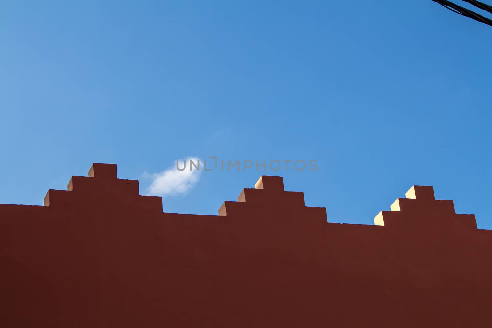 Edge of the fence with traditional decoration. Blue sky with a small cloud in the background.