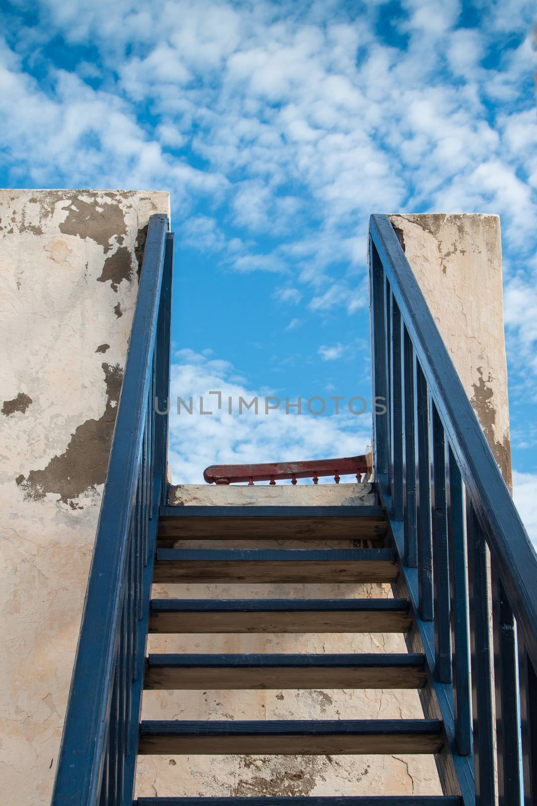 Blue colored stairs outdoors. Blue sky with tender white clouds.