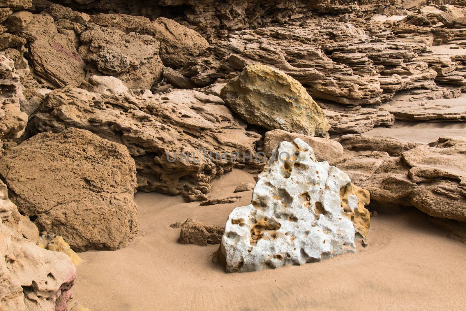 Sandy base of the beach at the Atlantic ocean shore in Morocco. Sandy colored rocks and white stone.