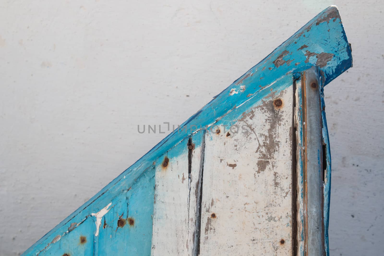 Triangle created by a detail of an old wooden boat, painted in blue and white.