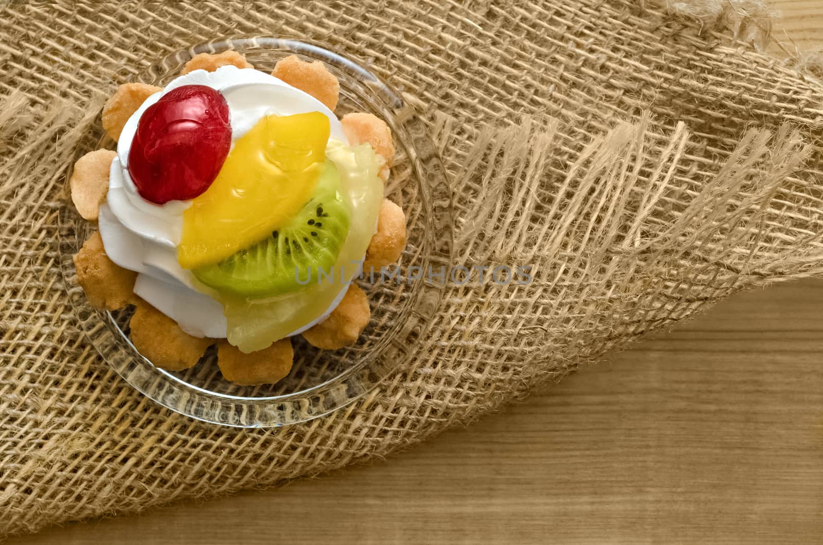 Cake with fruits and cream, on wooden table and burlap