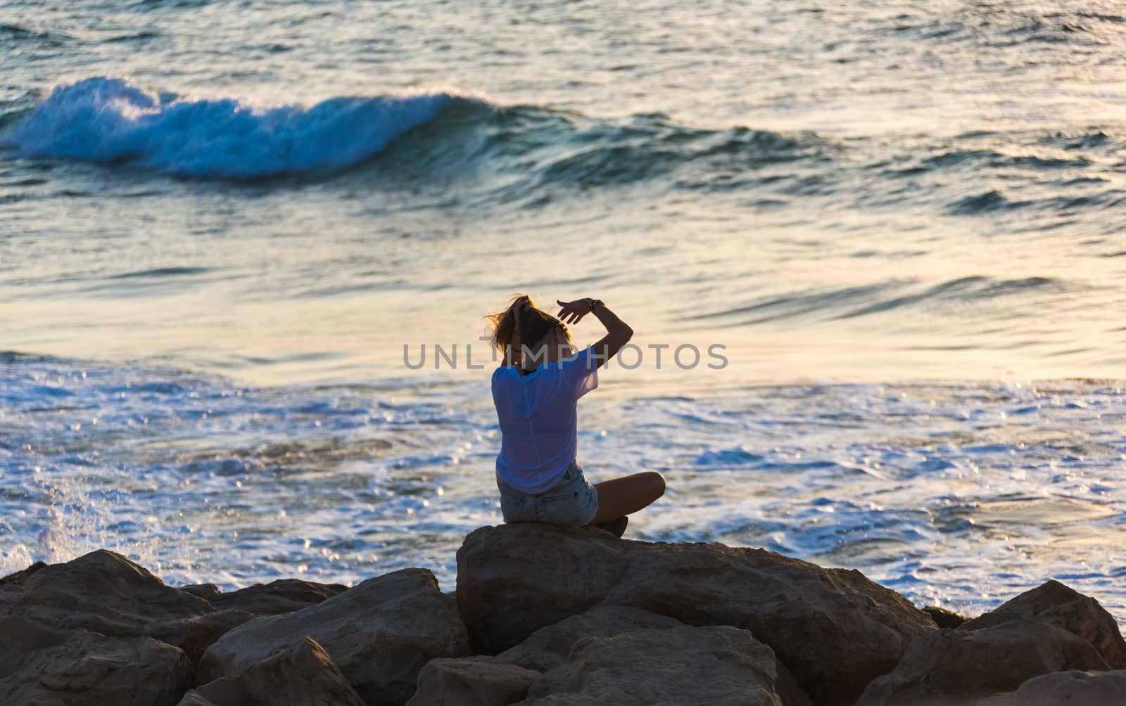 young woman sitting on the rocky seashore