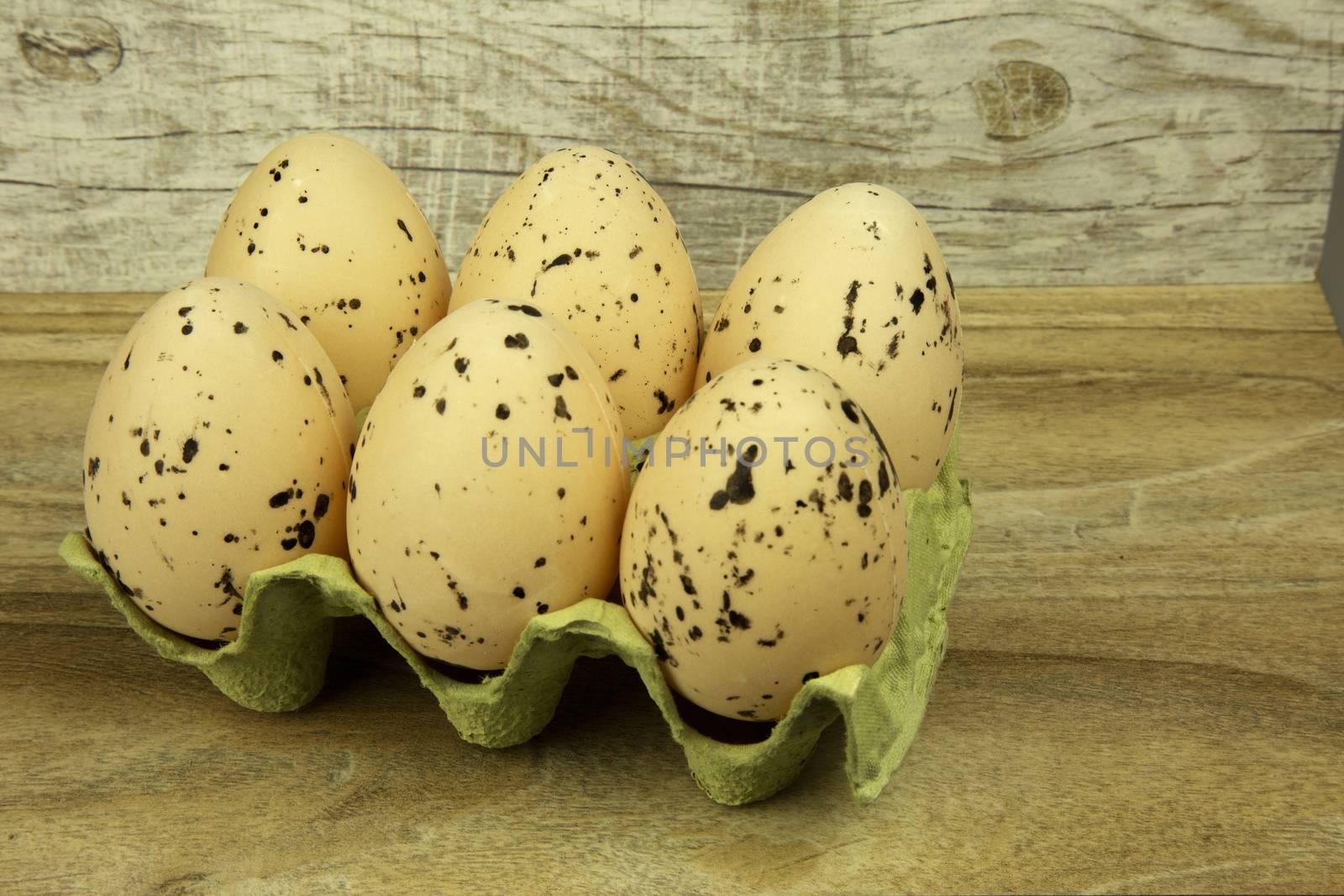 Six large white eggs with black spots in the mold. Easter decoration on the wooden background. Horizontal view.