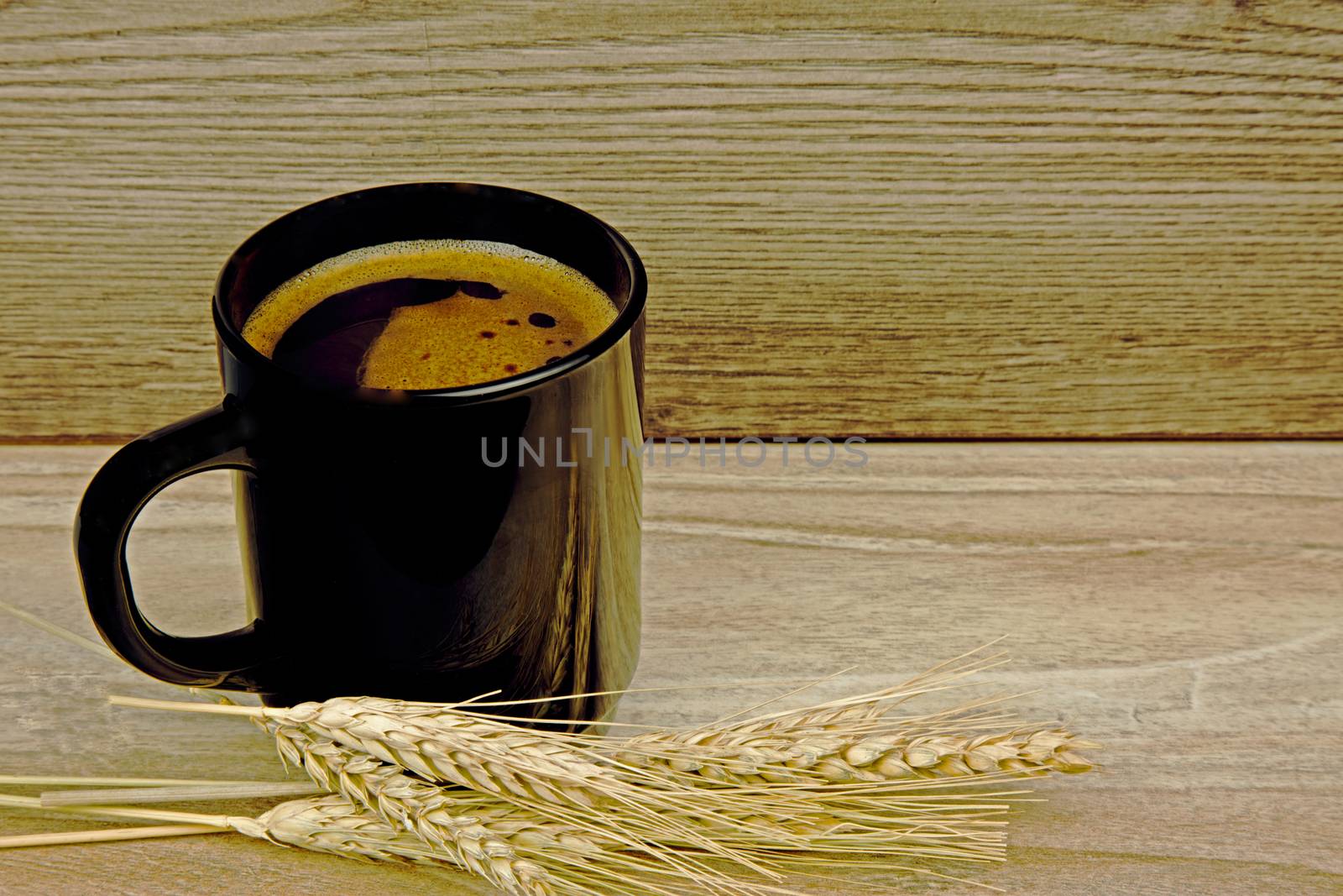 Cup of cereal coffe grain with two ears of corn grain cereals lying next to an old wooden table. Horizontal view.