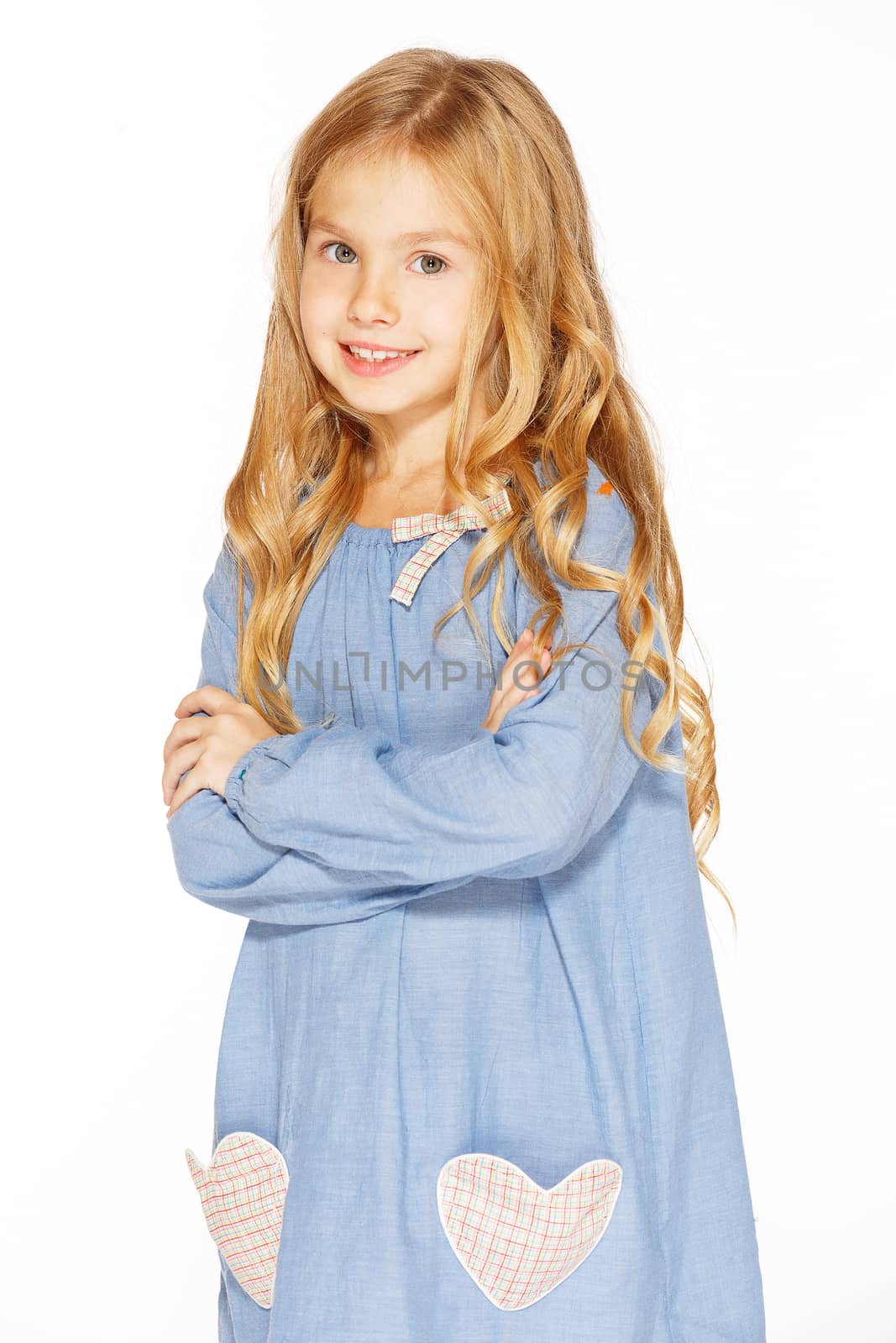 Little girl posing for the camera in blue dress with blond curls