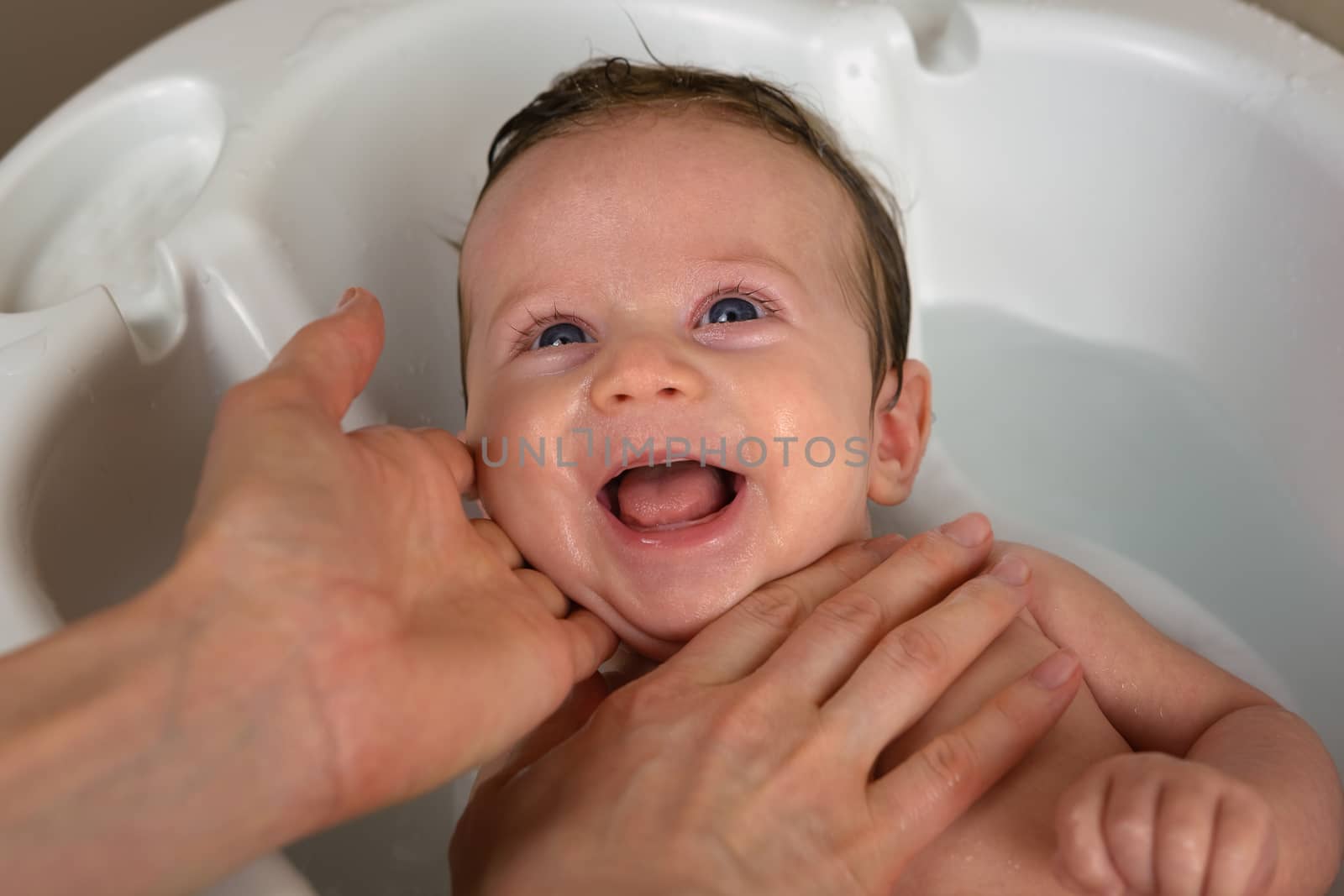 Newborn smiling while taking bath.