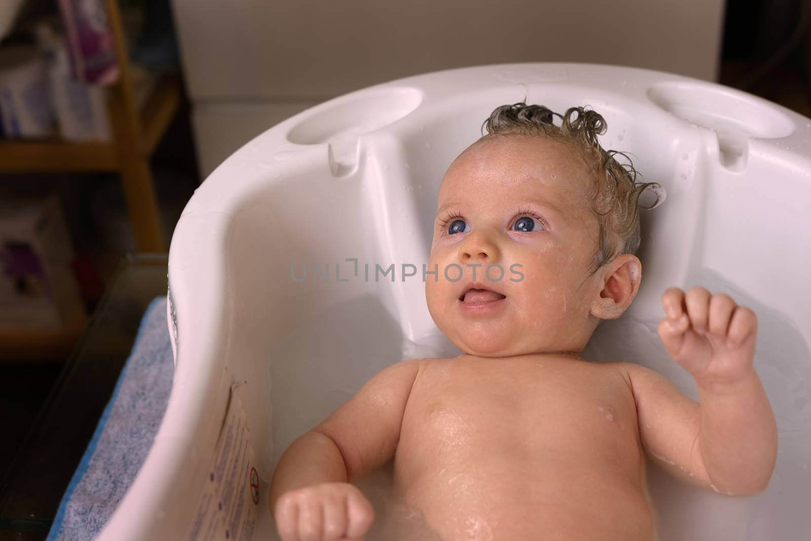 Newborn baby while taking bath with foam and shampoo on the hair