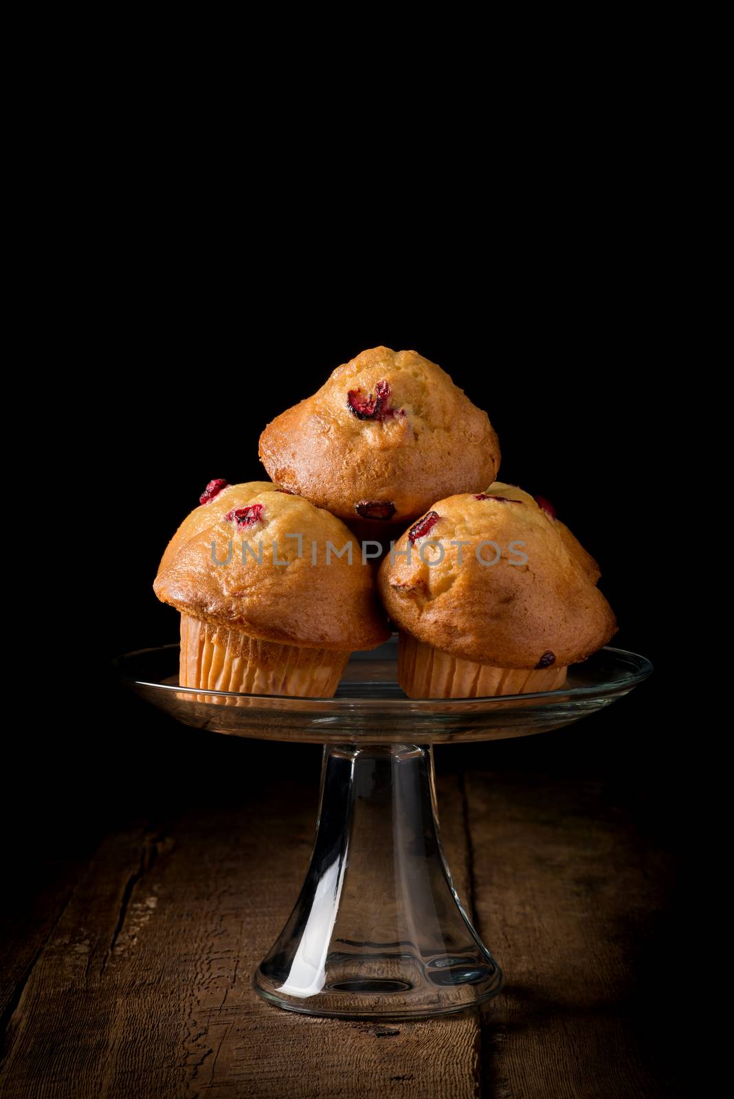 Lemon Cranberry Muffins photographed on a low key background.