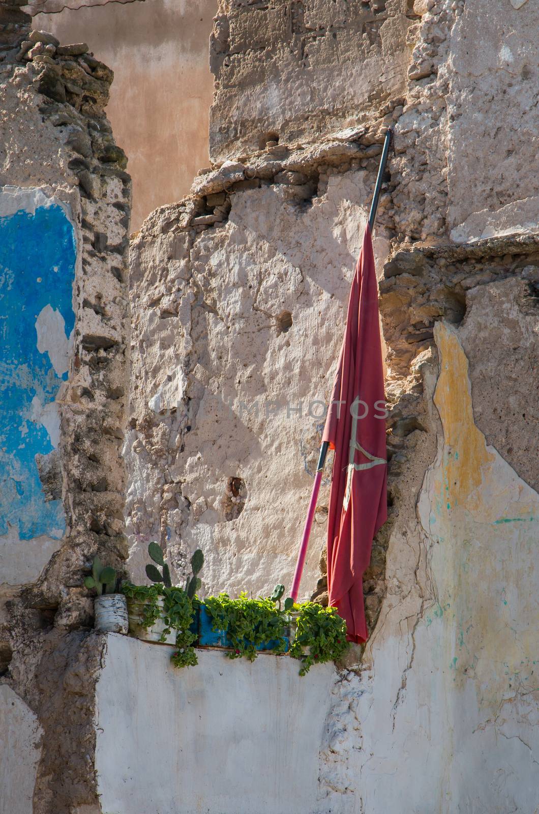 Ruins of an old demolished house. Structure of the walls remaining. Moroccan flag and fresh plants in the pots.