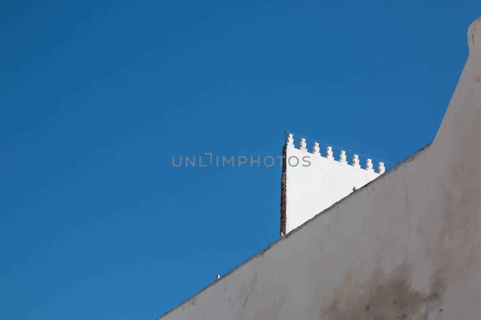 Diagonal view on the white arabian architecture. Bright blue sky.