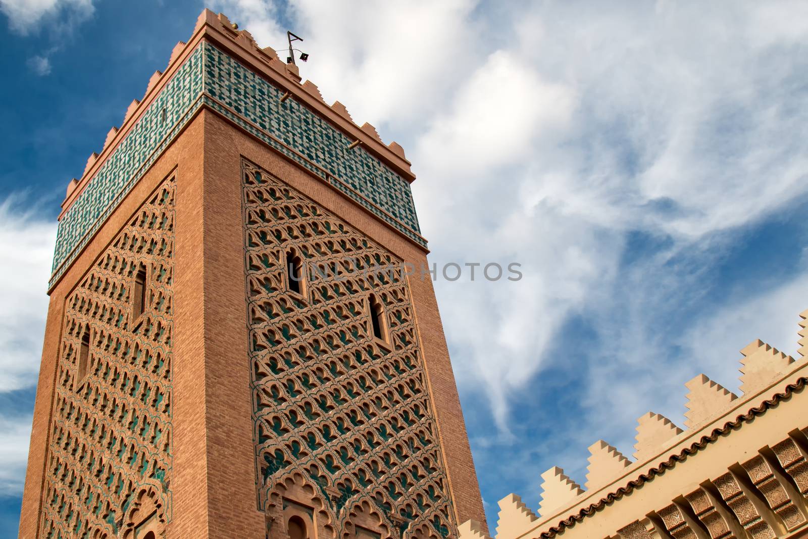 Tower of a famous mosque in medina of Marrakesh. Traditional details of the arabian architecture. Cloudy sky.