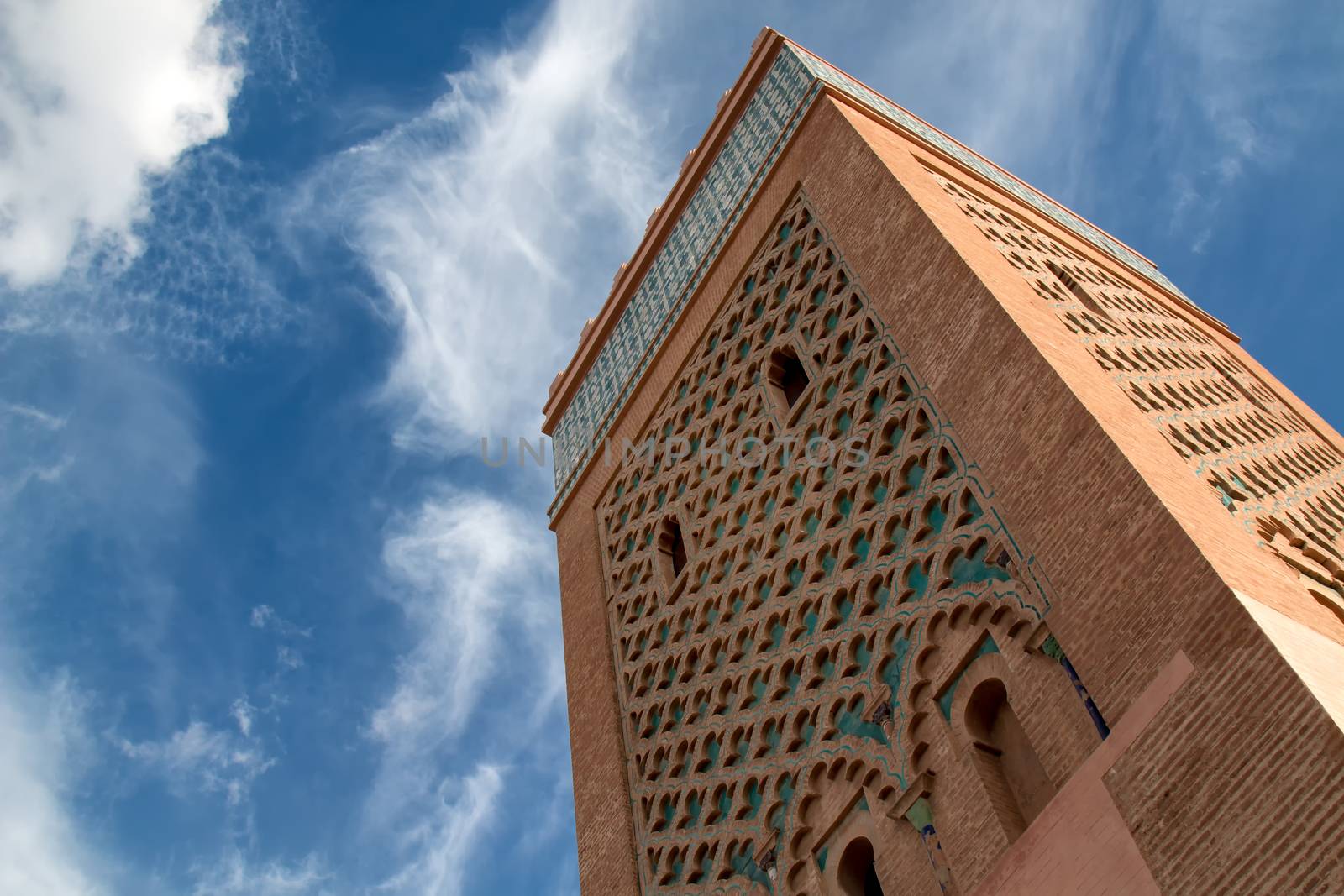 Tower of a famous mosque in medina of Marrakesh. Traditional details of the arabian architecture. Cloudy sky.