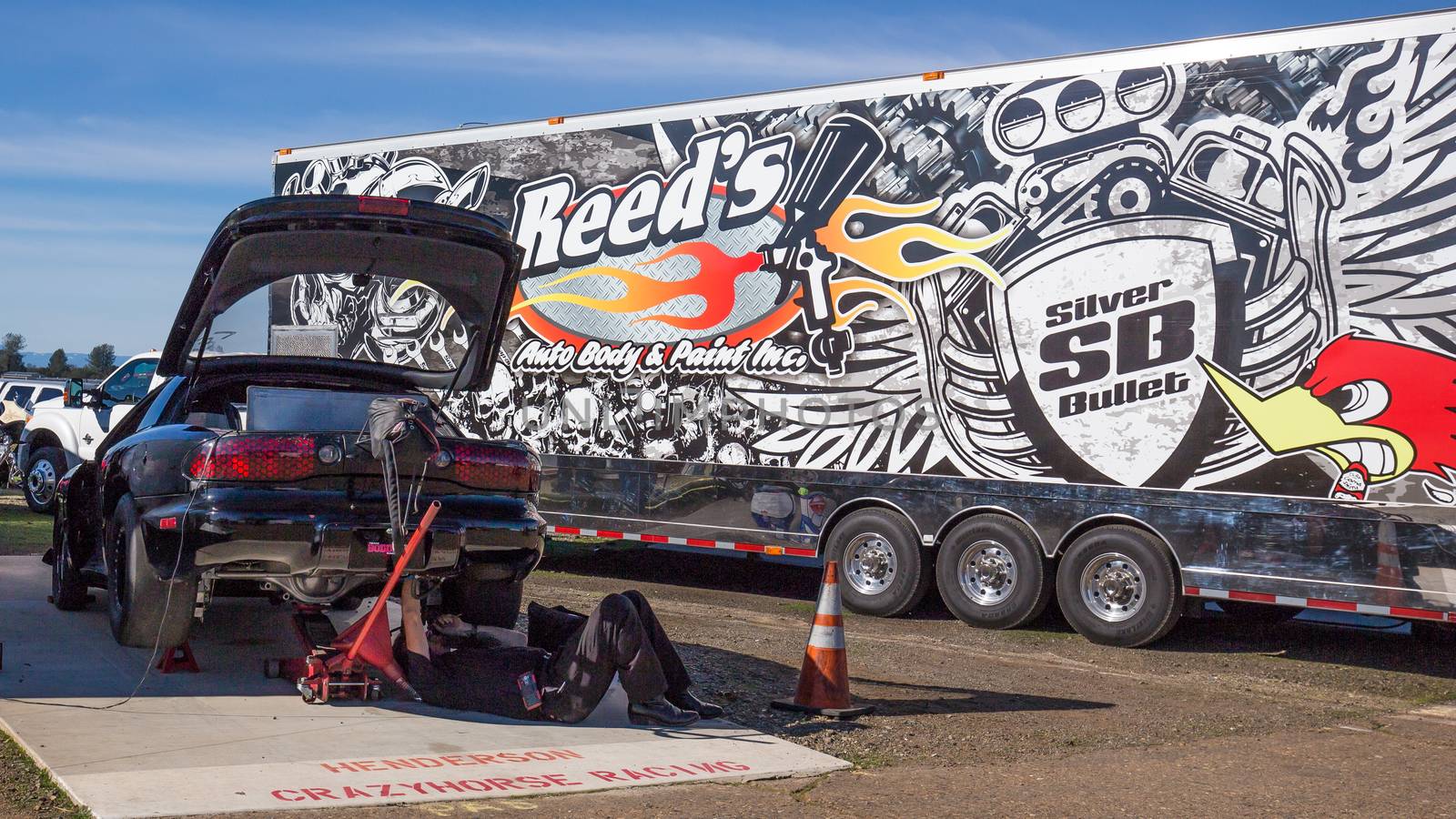 Redding, California, USA- February 13, 2016: A mechanic is under a hot rod to make last minute repairs before the start of drags at the Redding Drags in northern California.