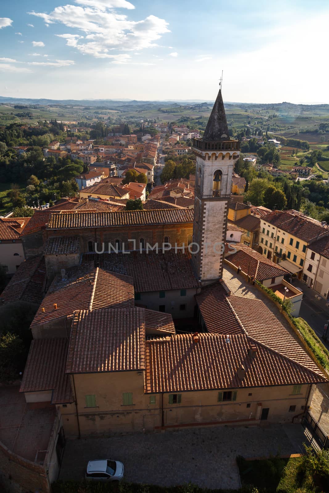 Top view of Vinci Village around meadow area from Conti Guidi Castle in Italy, under bright blue sky background.