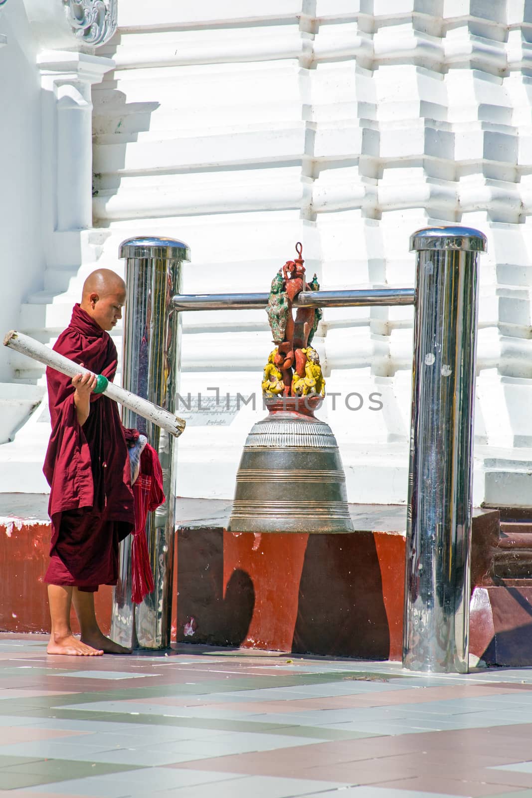 YANGON, MYANMAR - NOVEMBER 25, 2015 - Buddhist monk ringing the bell in the Shwedagon Pagoda on November 25, 2015 in Yangon. The Pagoda is the most famous buddhist temple in Myanmar.