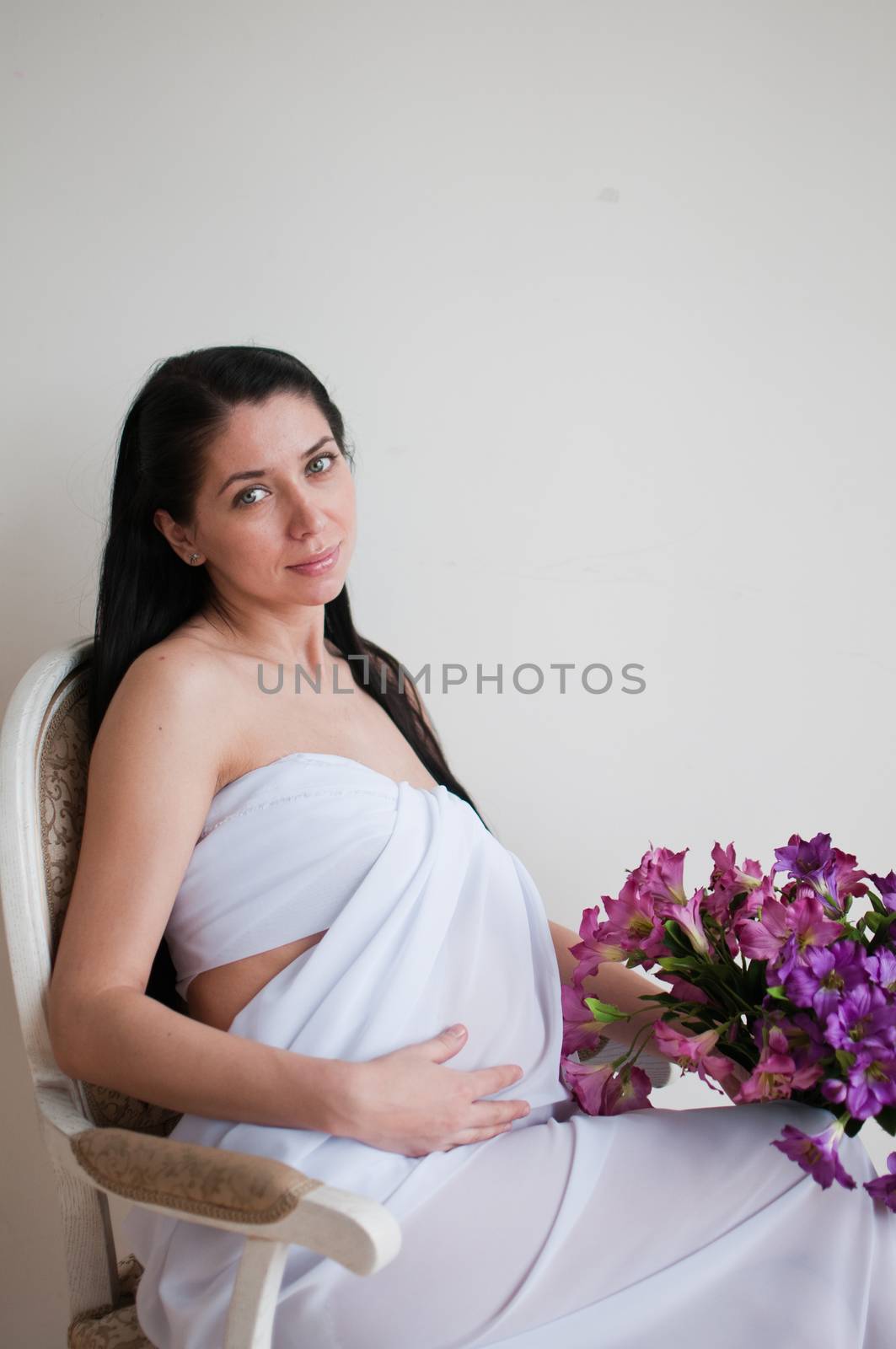 Vertical portrait of the sitting pregnant woman