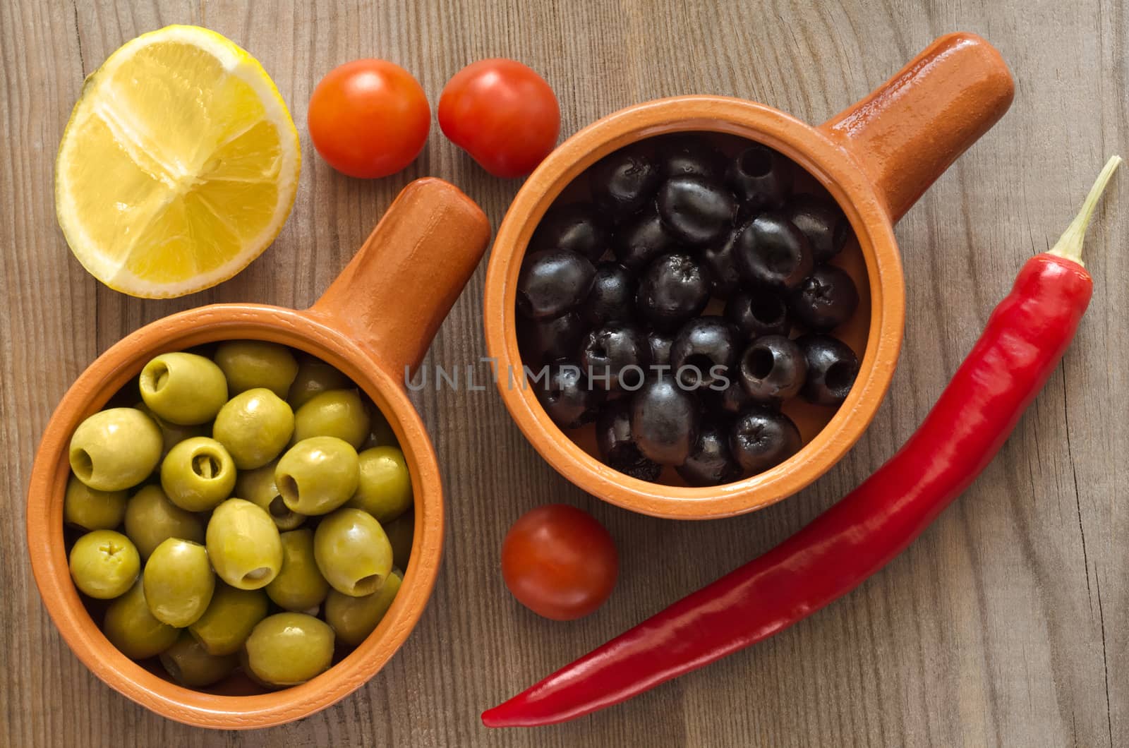 Olives in cups on a wooden table by Gaina