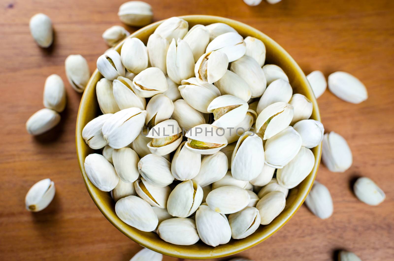 pistachio nuts in a  bowl on wooden table