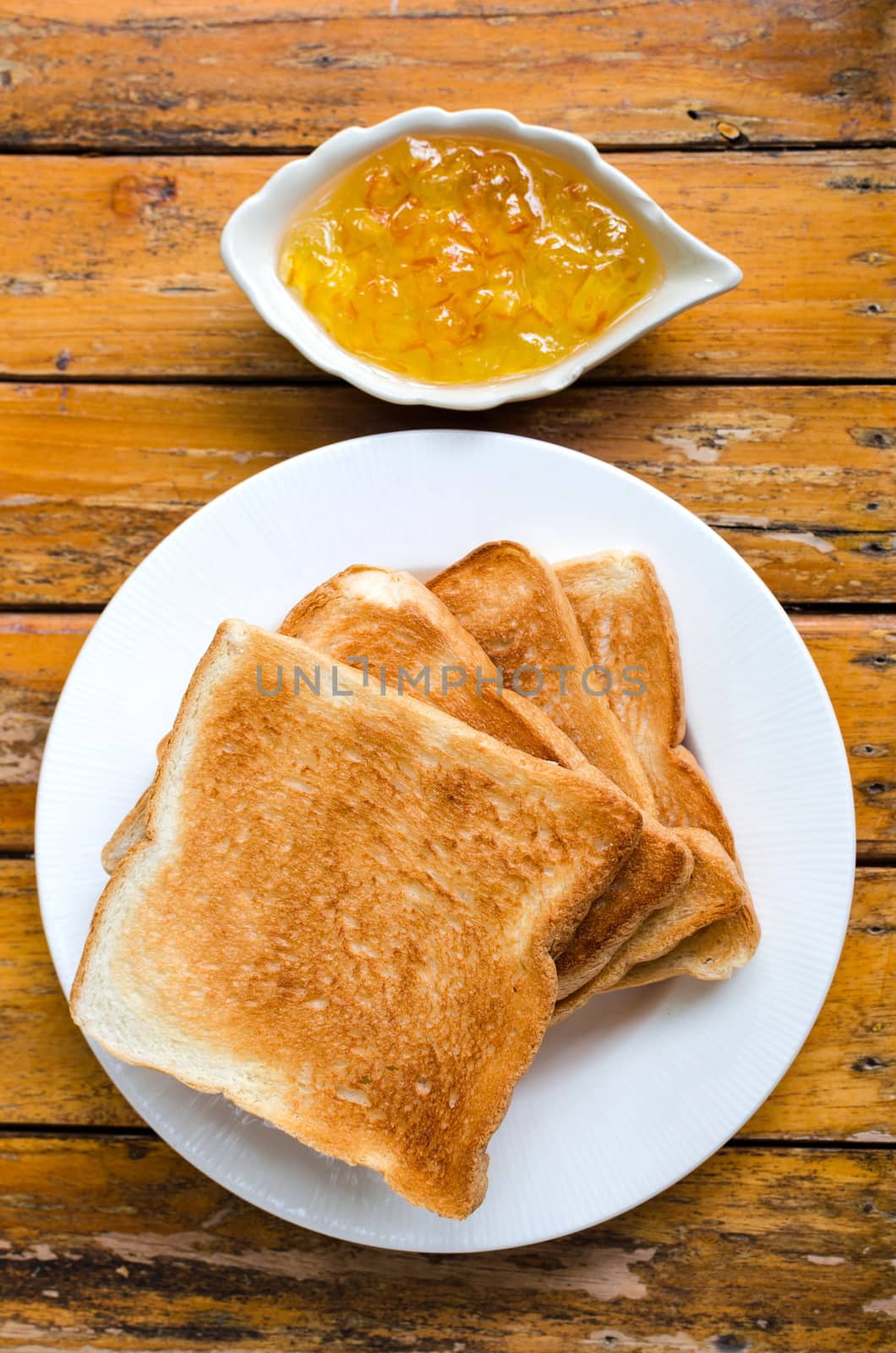 Slices of toast bread with orange jam on wood background