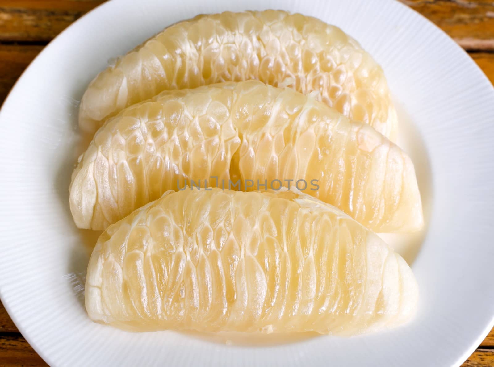 Thai pomelo fruit Peeled in white dish on wood table.