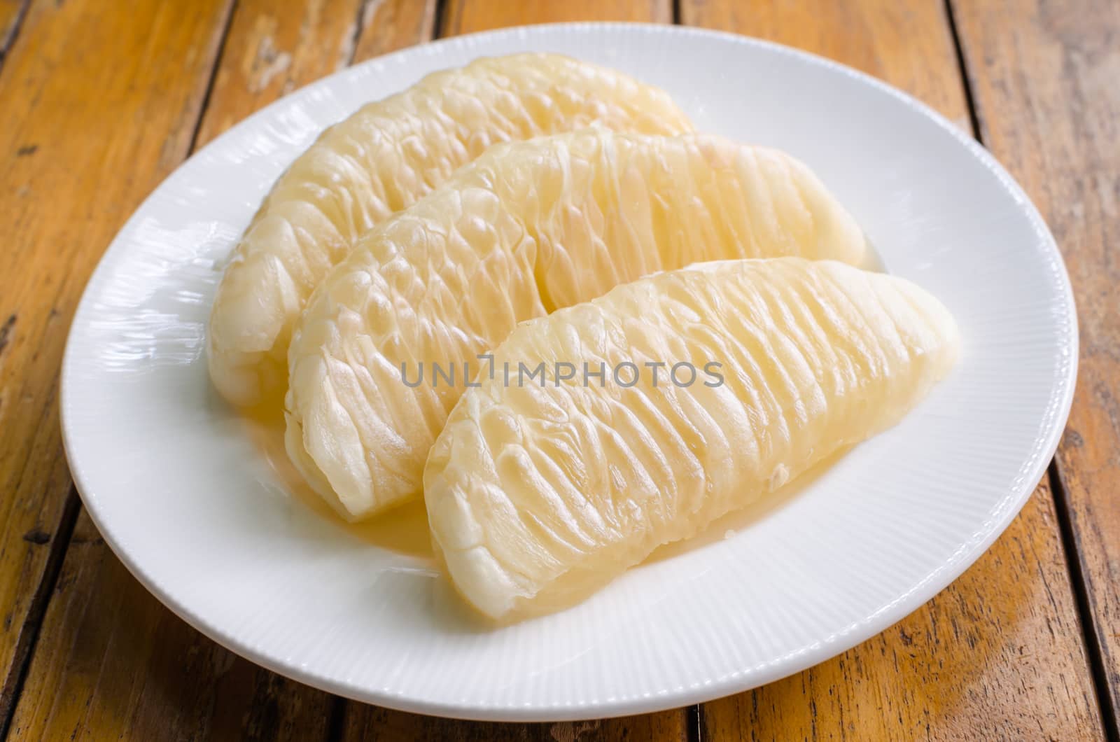 Thai pomelo fruit Peeled in white dish on wood table.