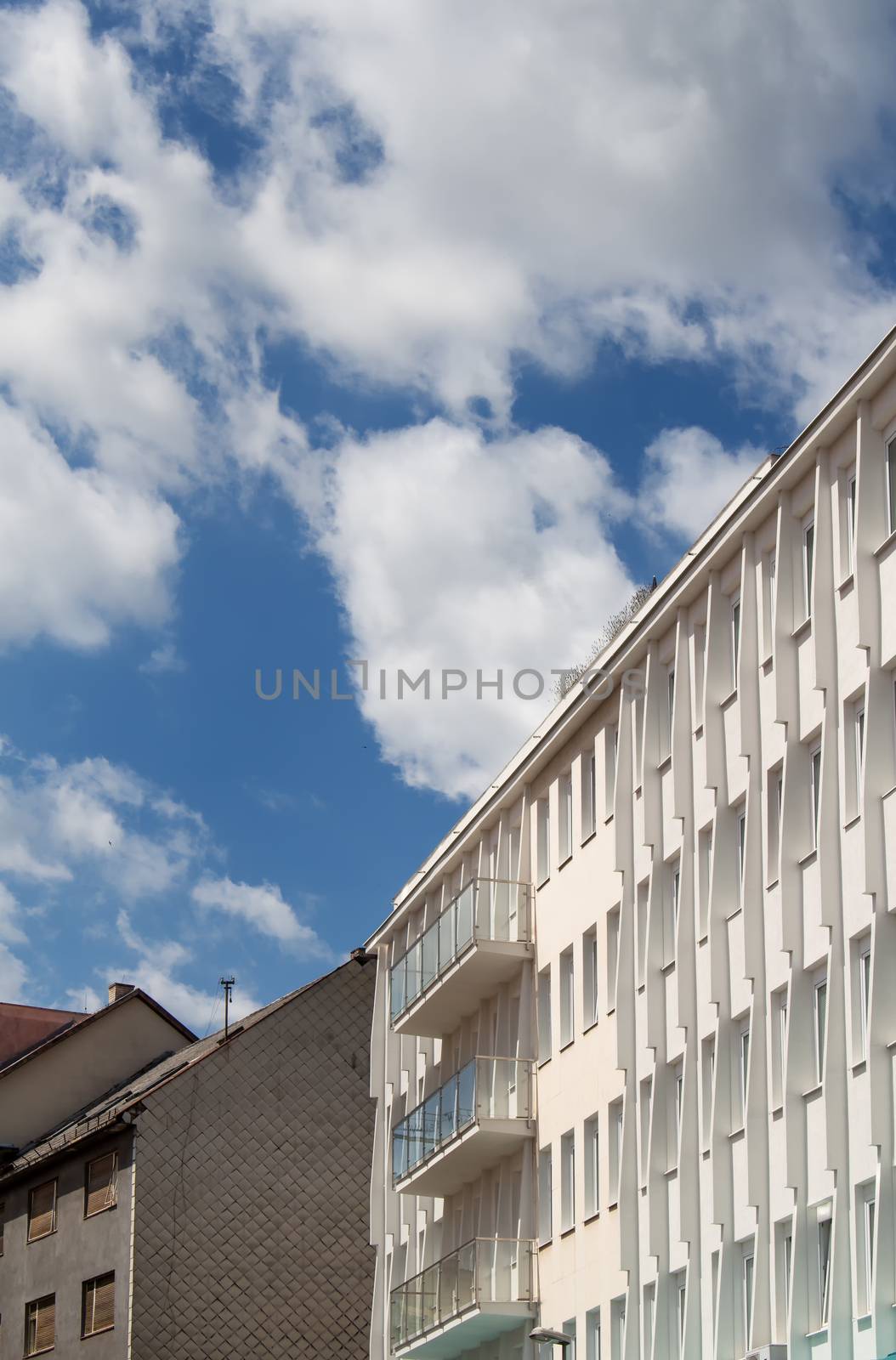 Detail of a modern building. Contrast bright blue sky with white clouds.