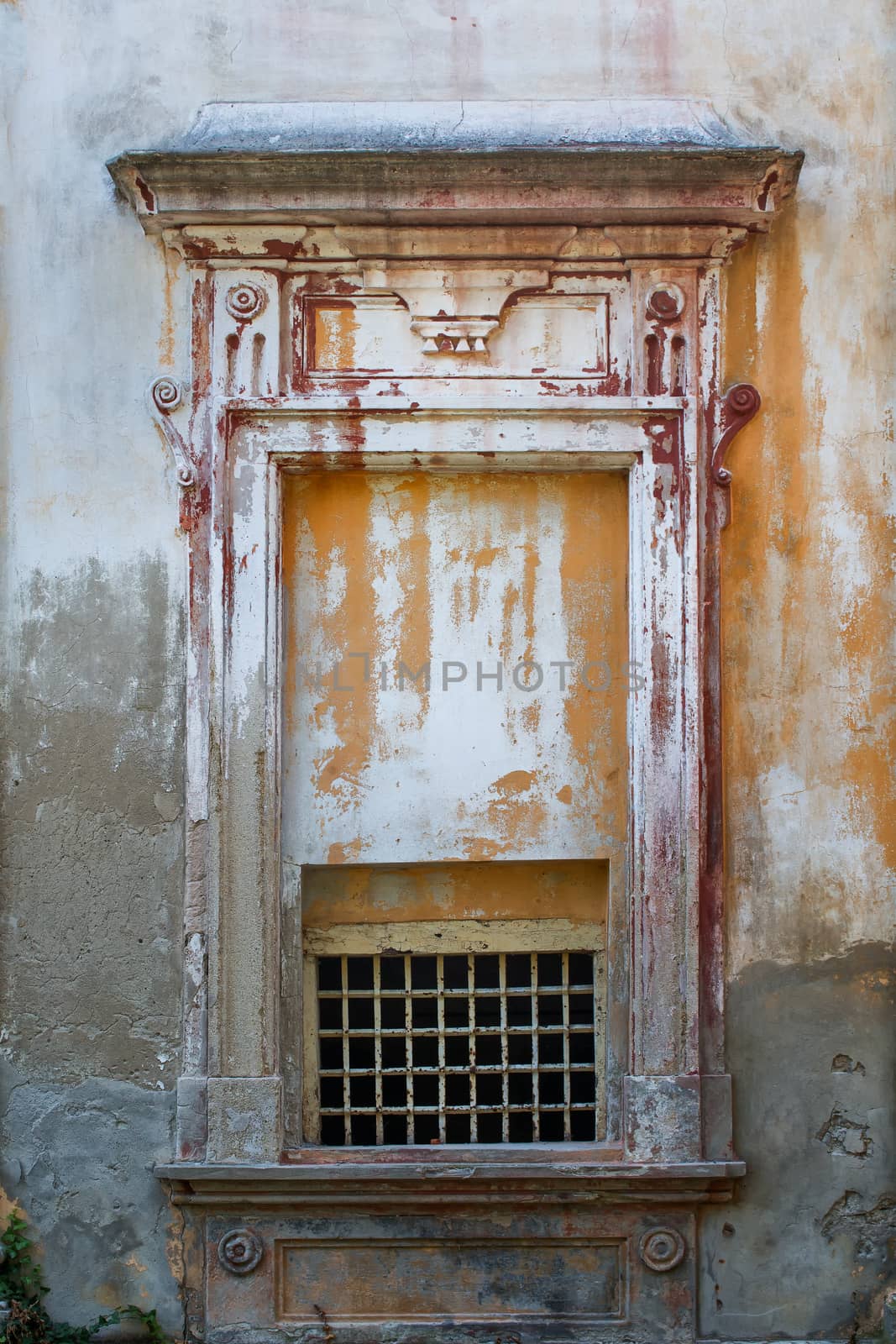 Old walls of an abandoned manor-house. Decorative window, part of facade, just with small grid to get the air inside.