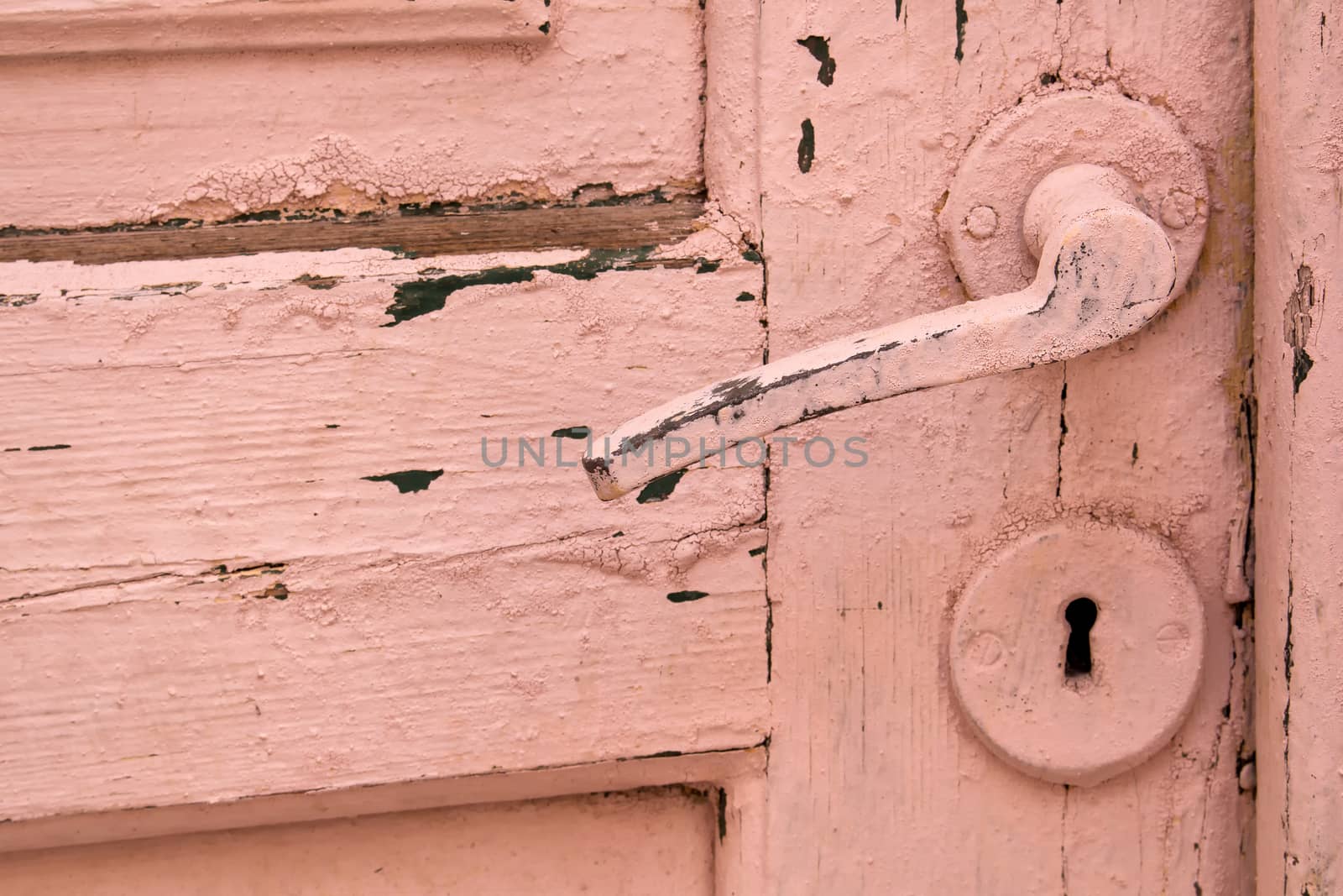 Old wooden door, painted with rose color, including the lock and handle.