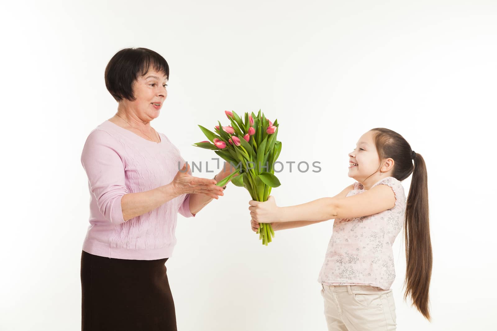 the granddaughter congratulates the grandmother and gives it flowers