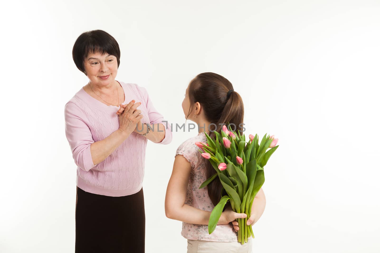 the granddaughter hides a bouquet of flowers for the grandmother by sveter