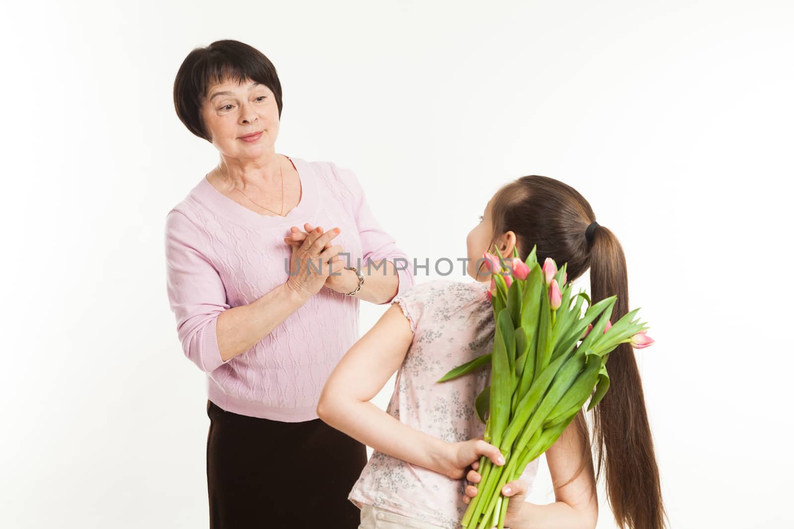 the granddaughter hides a bouquet of flowers for the grandmother by sveter