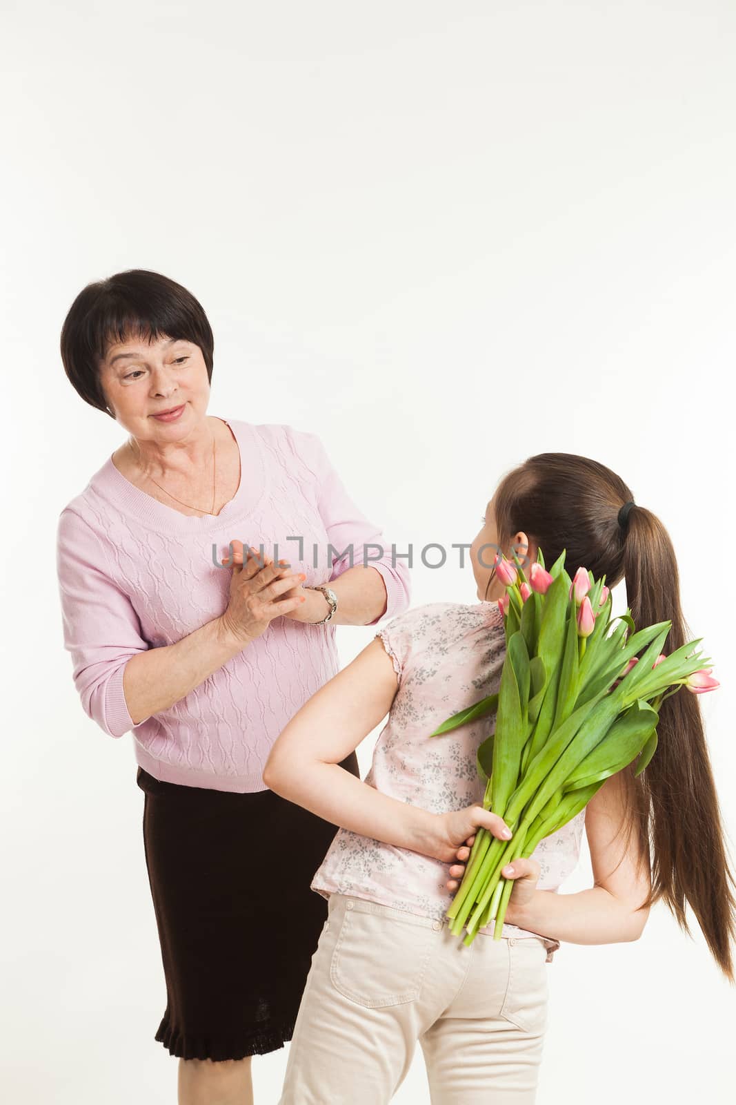 the granddaughter hides a bouquet of flowers for the grandmother by sveter