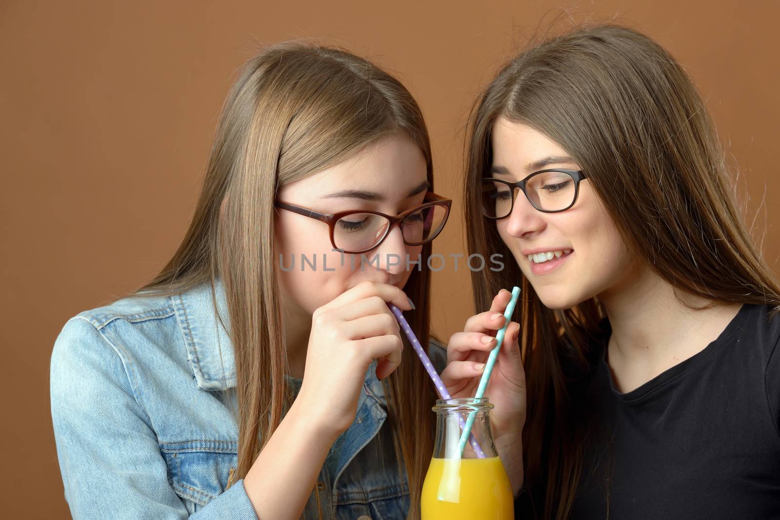 Girls sharing an orange juice drink 