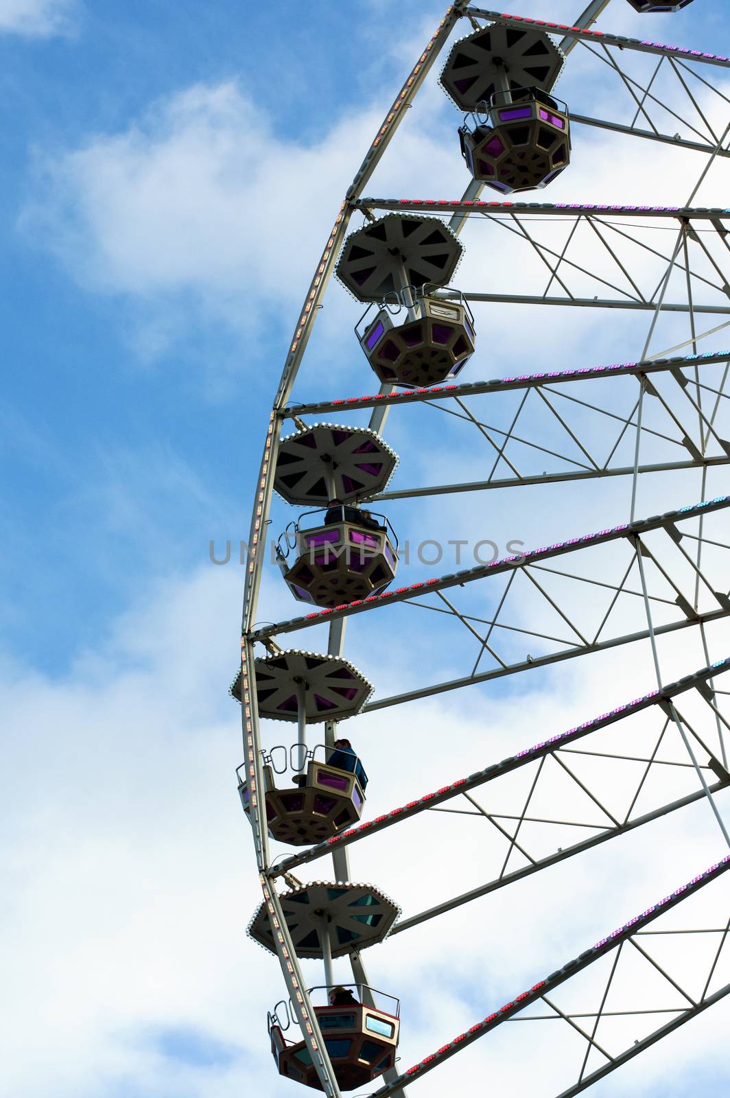 White and Pink Ride Ferris Wheel on Blue Cloudy Sky background Outdoors