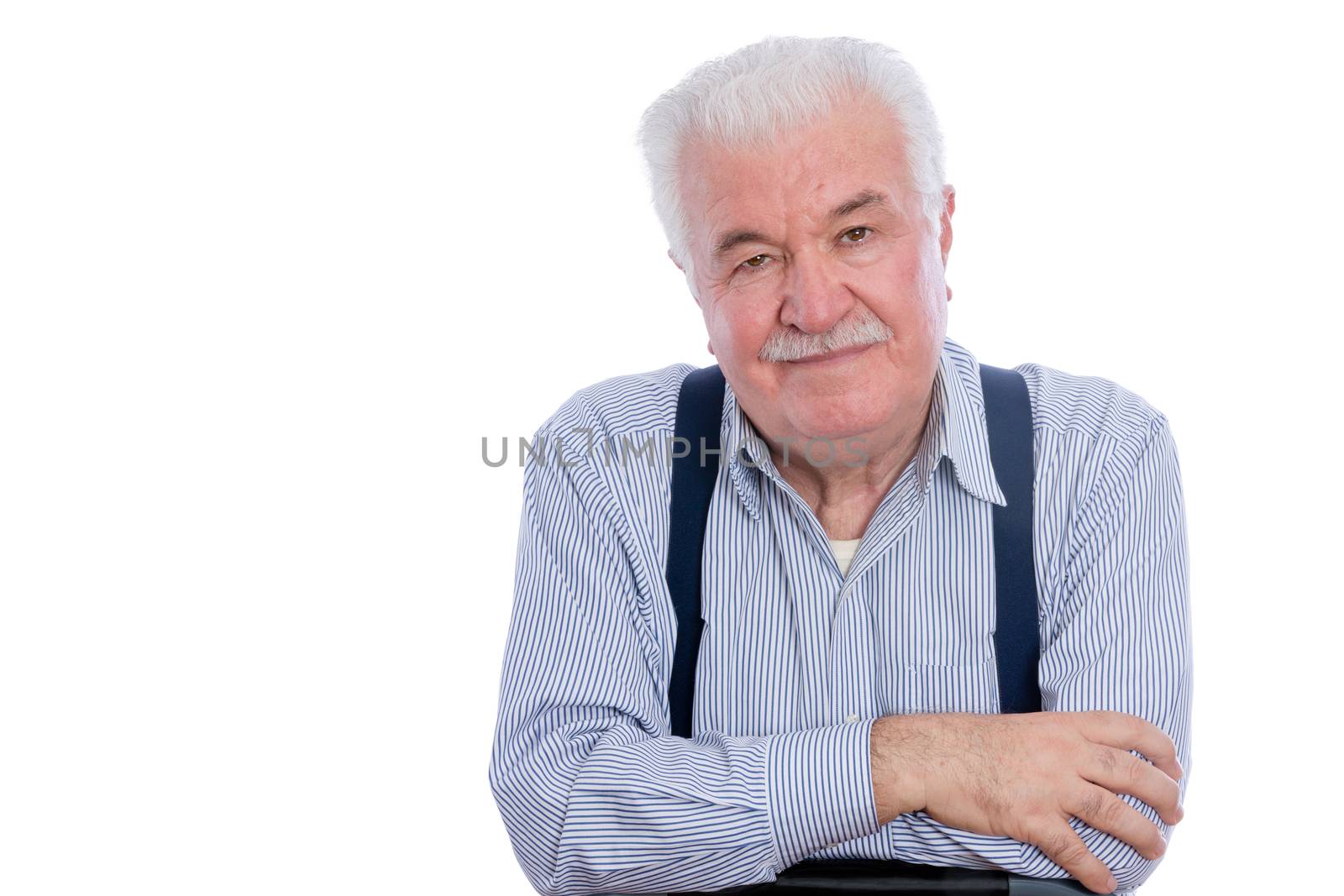 Handsome senior man in white striped shirt and blue suspenders with calm expression and folded arms