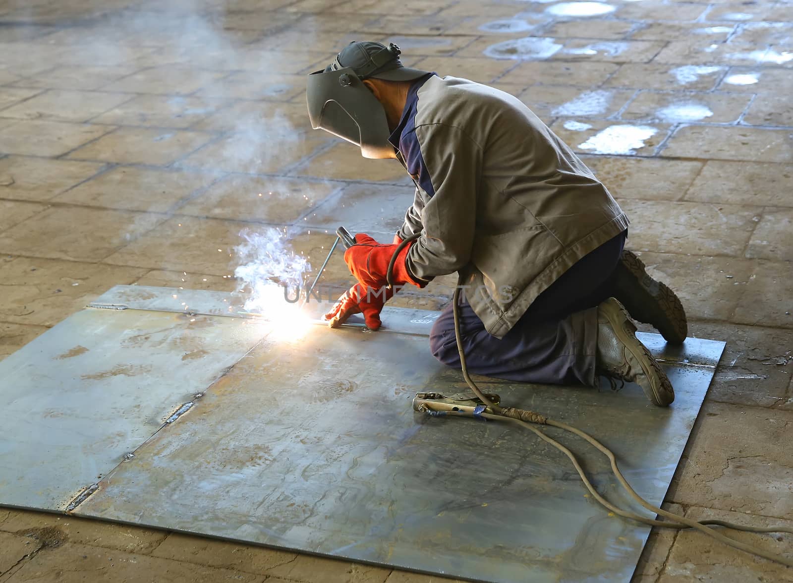 Welder in factory. A worker welds a steel sheet by sergasx