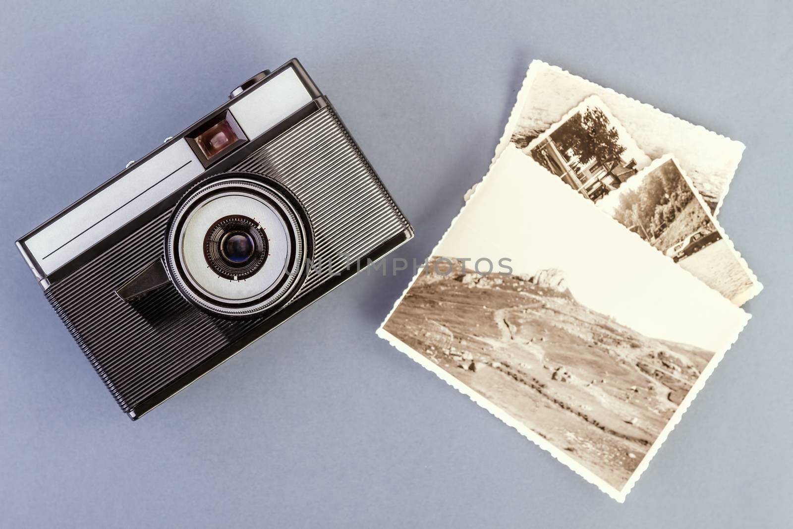 Vintage photo camera and old photos on a gray table