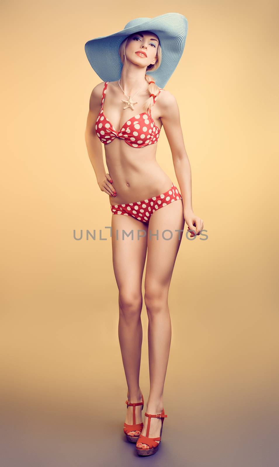 Sexy PinUp woman in fashion red polka dots swimsuit, blue hat, beach slim body. Playful blonde sensual girl in bikini. Summer holiday, sea vacation. Yellow, vintage toned, unusual creative provocative