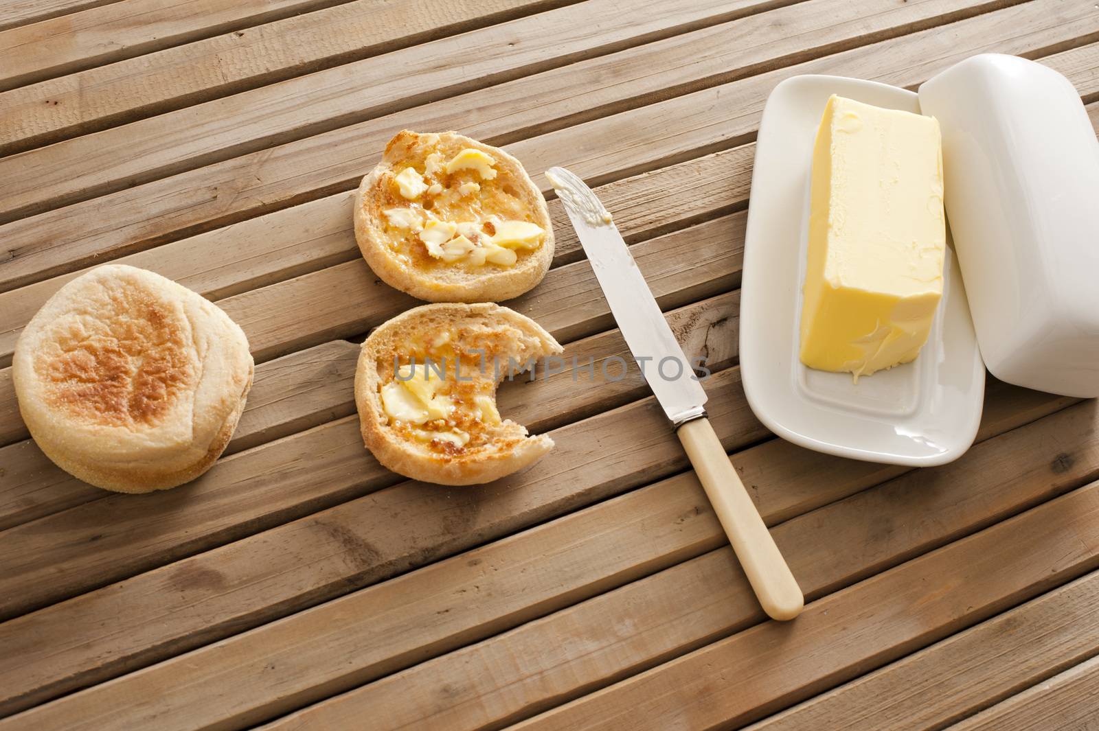Buttered crumpets with a pat of farm butter by stockarch