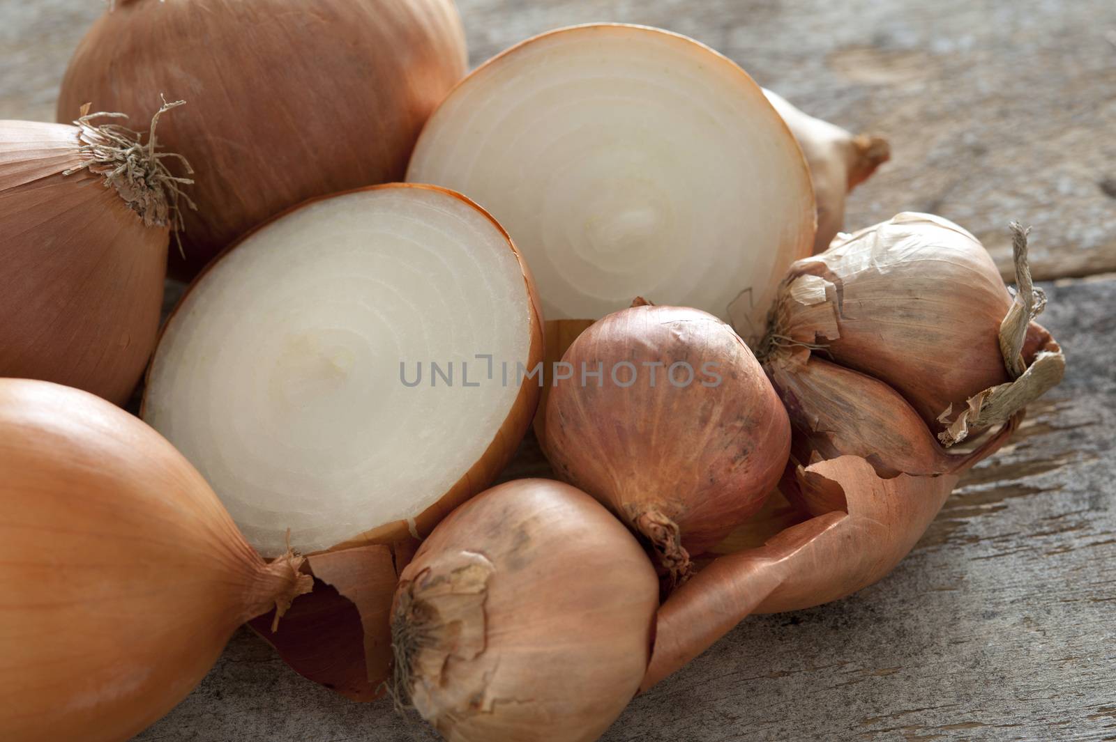 Pile of fresh whole and halved brown onions on a kitchen counter for use as a cooking ingredient or accompaniment to a meal