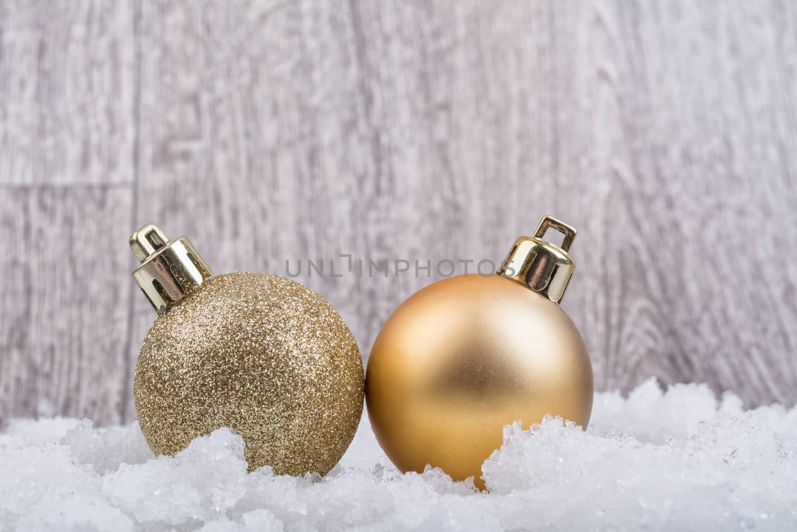 Two christmas balls on the snow with wooden background