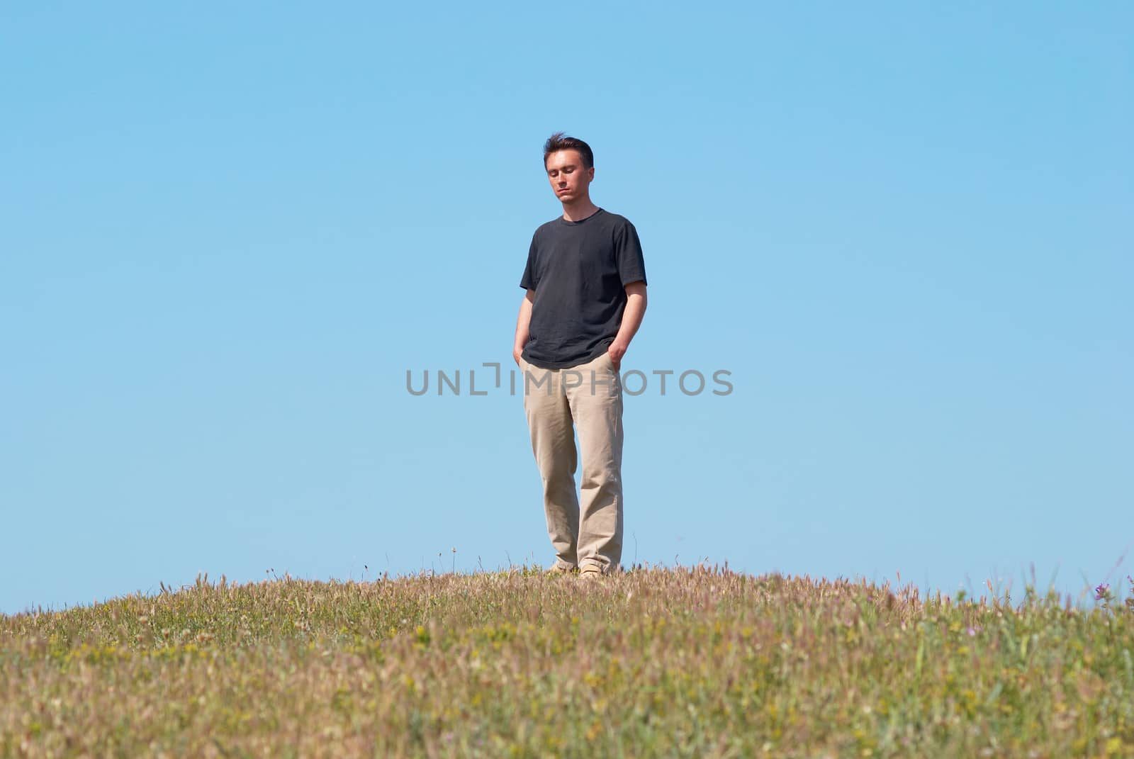 Young man on the grass field with blue sky