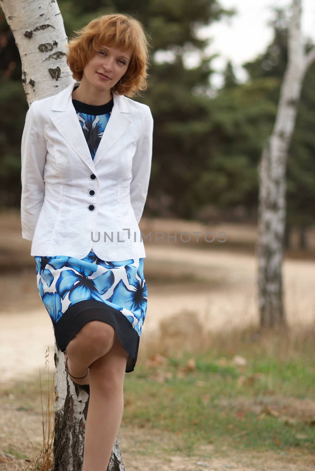 Beautiful woman standing near birch with soft background