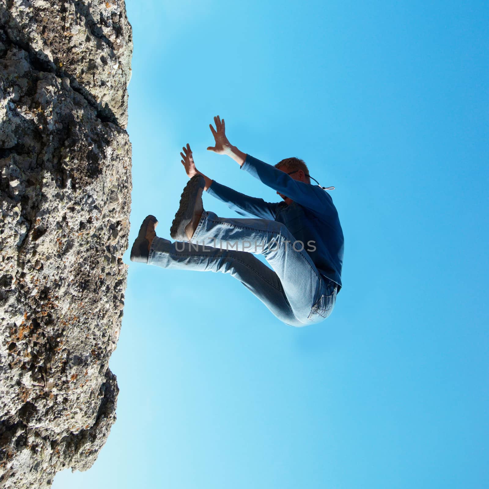 Falling down man from the rock with blue background